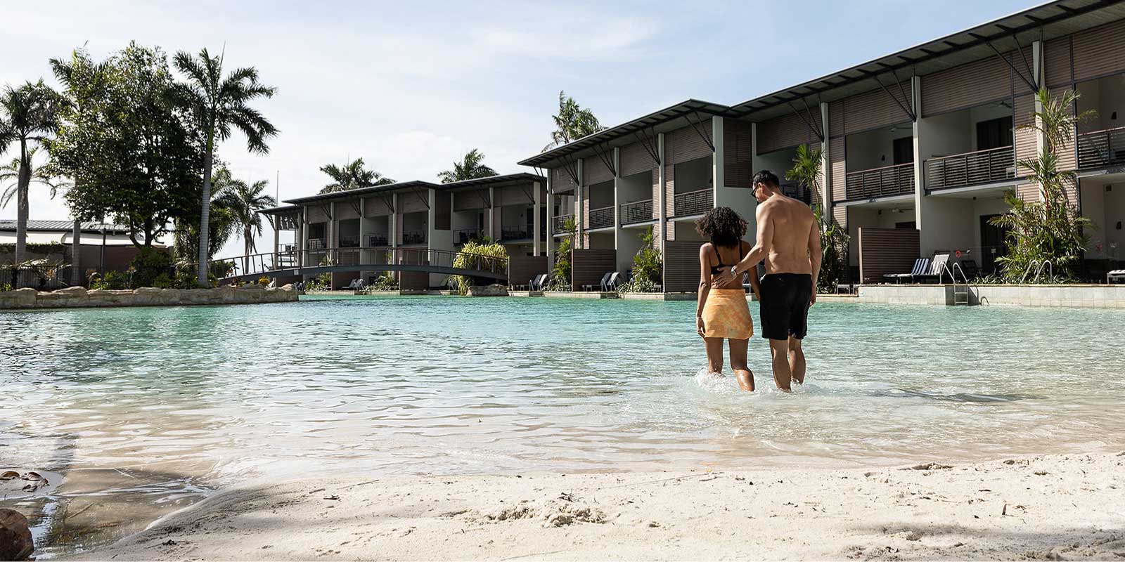 Couple walking into the water at the beach.