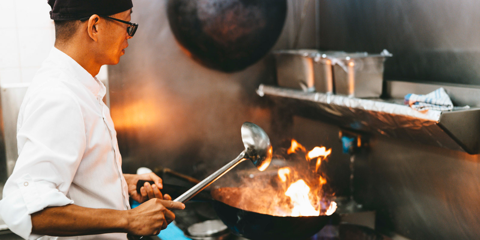 A chef cooking delicious food with a ladle and wok