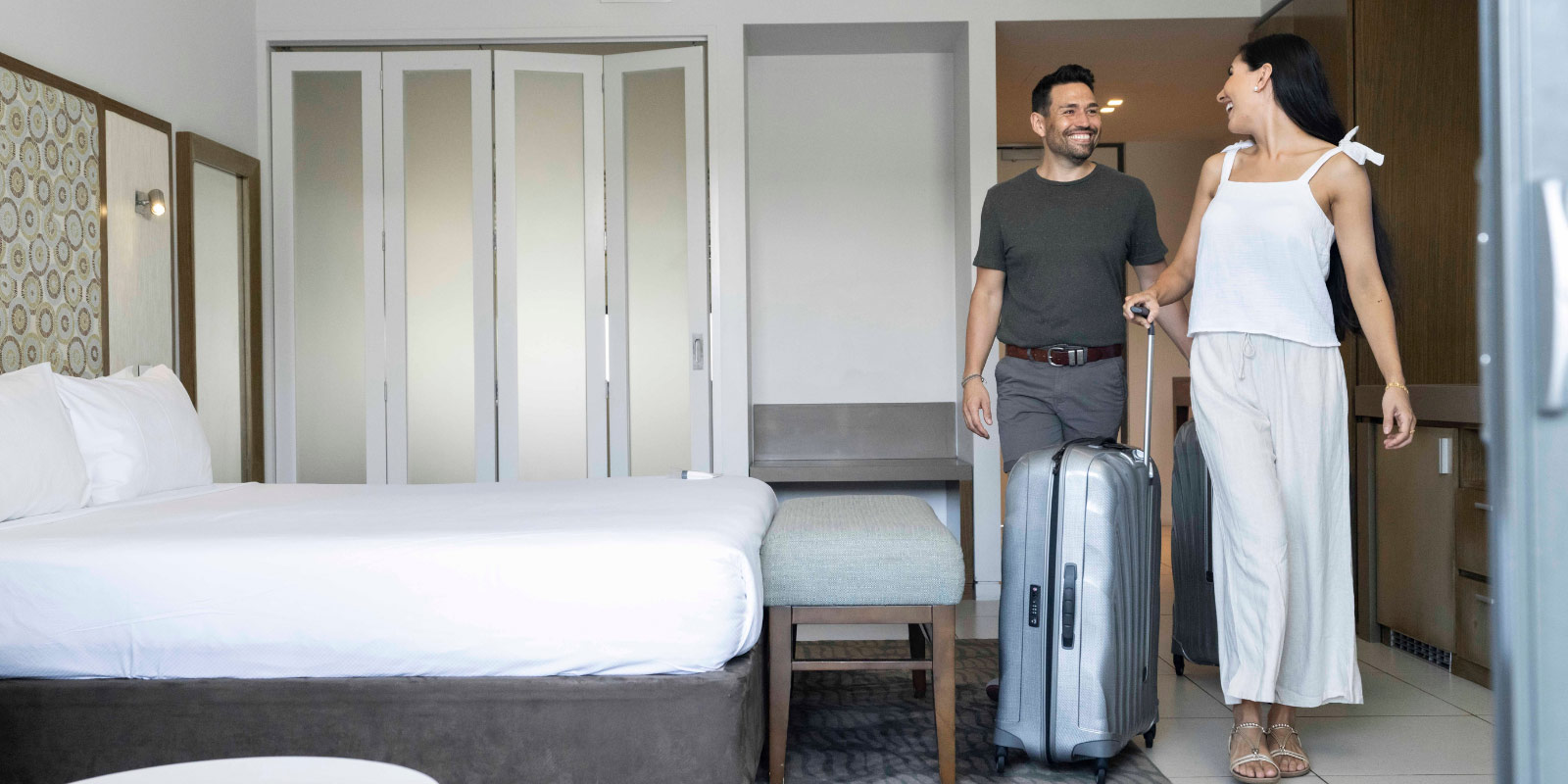 Couple smiling walking into their hotel room.