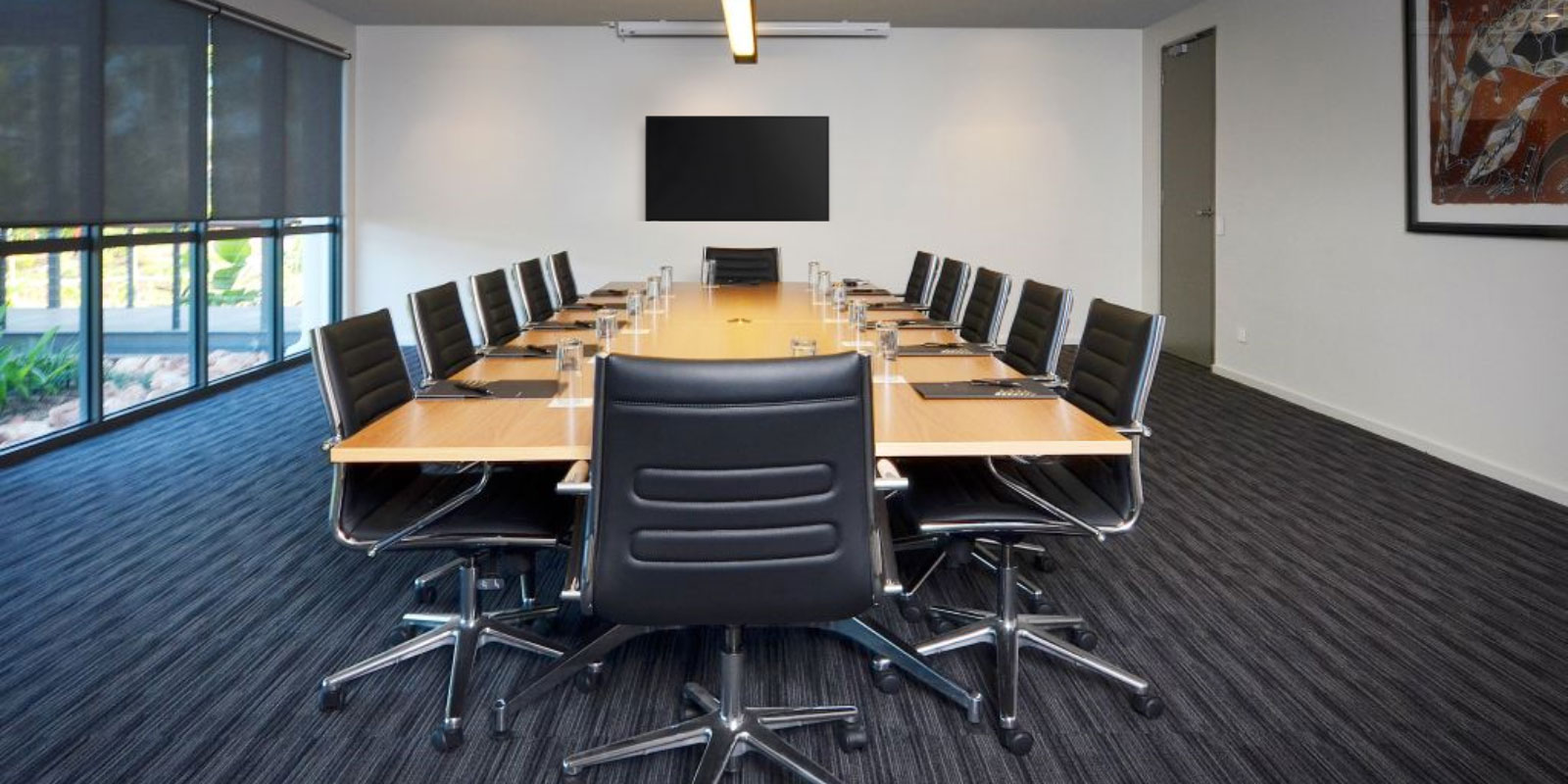Corporate board room filled with leather chairs, tv, and table