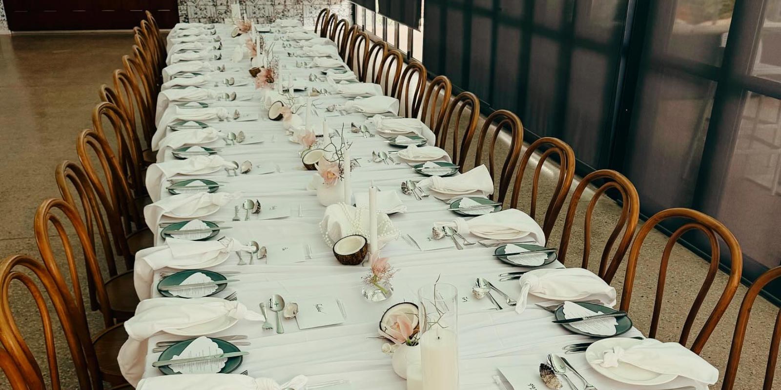 Formal table set with a line of wooden chairs on either side.