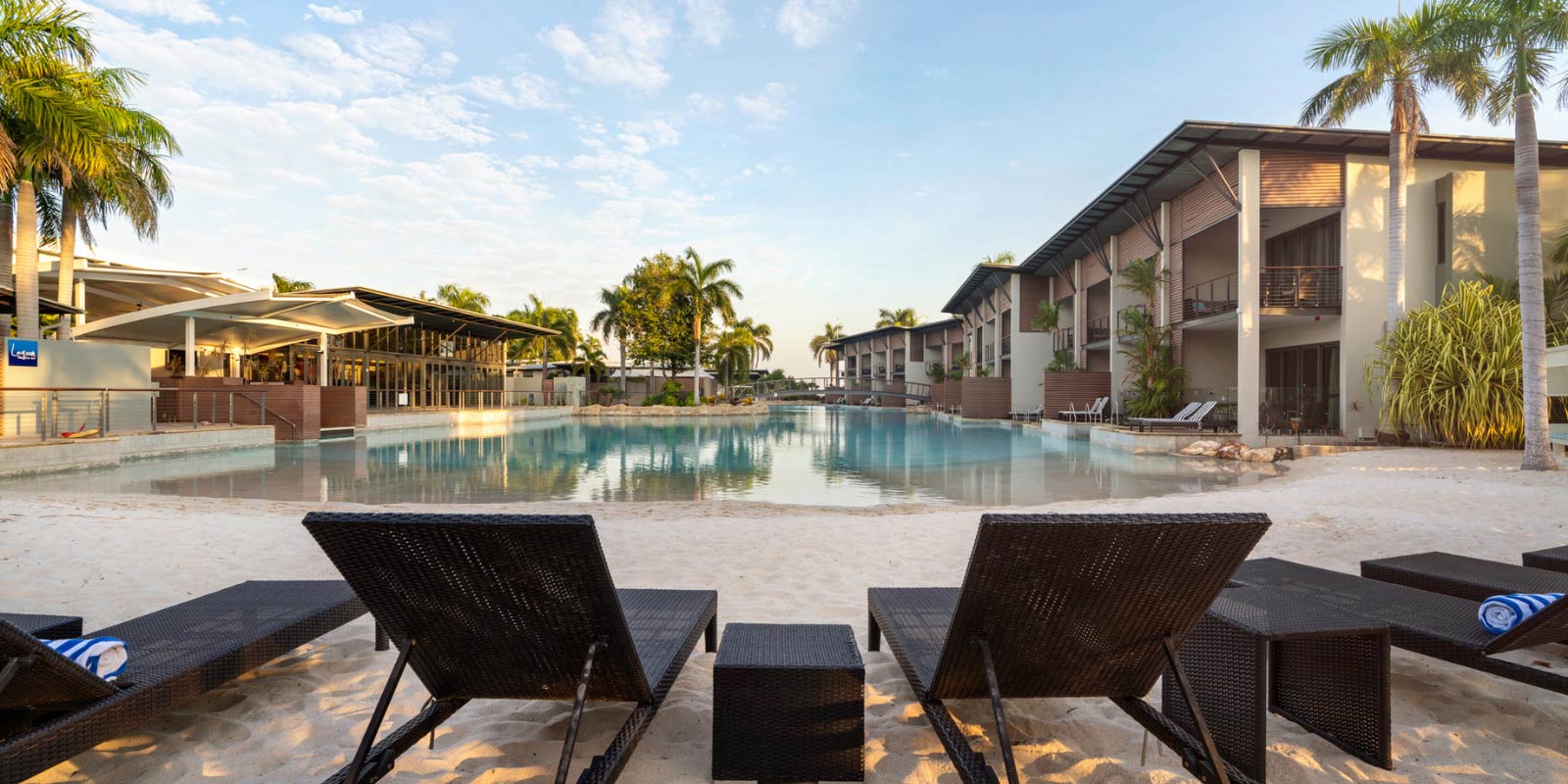 Patio chairs on the beach facing the entrance of the pool area.