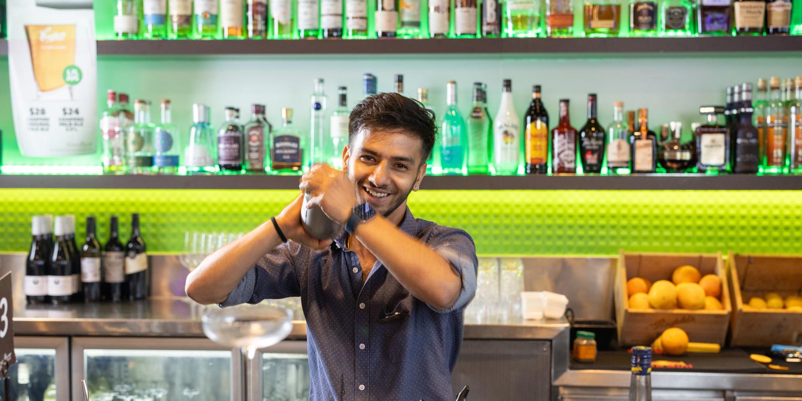 Bartender shaking a mixed drink behind the bar.