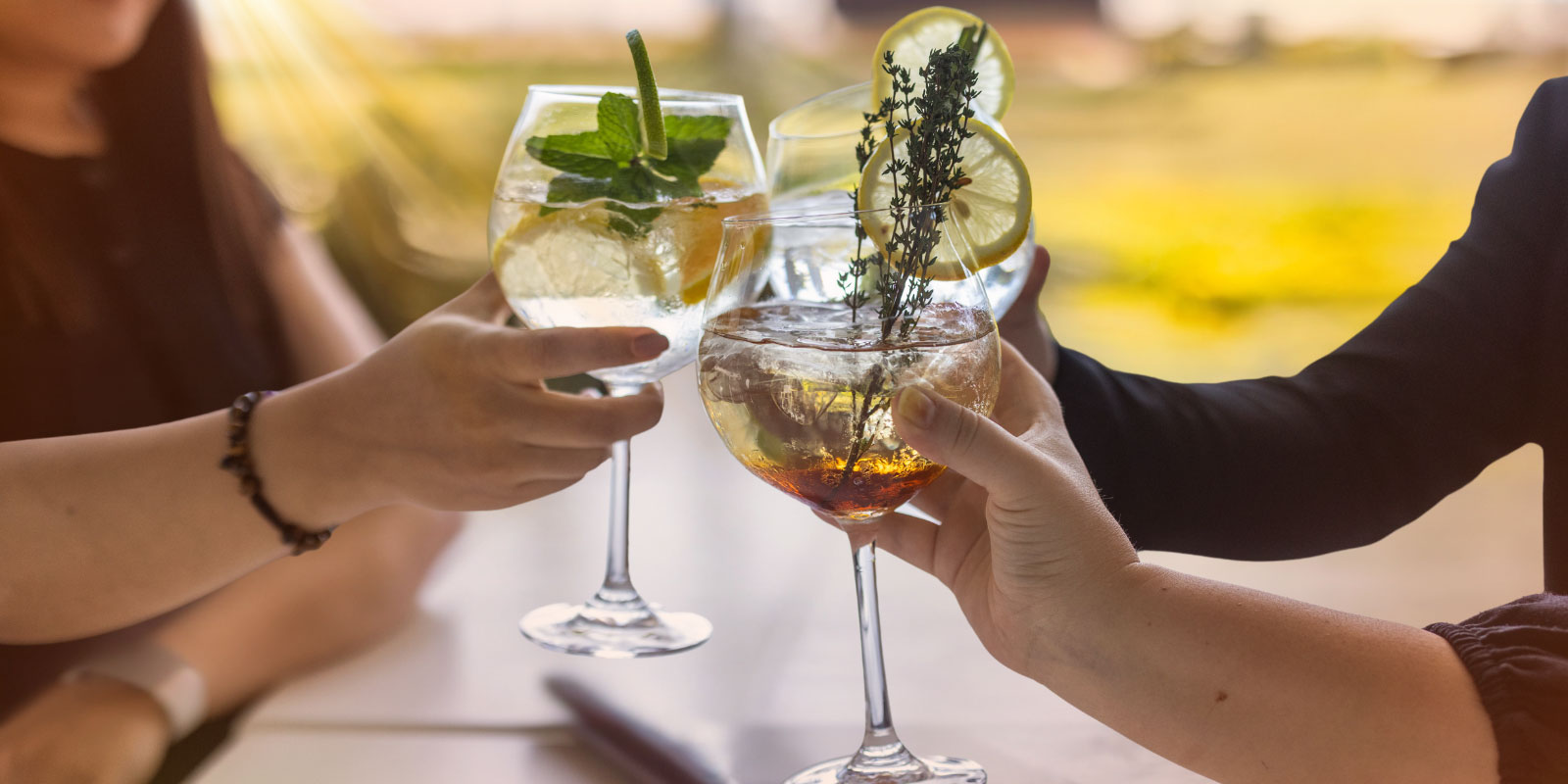 Group of friends toasting with various cocktails.