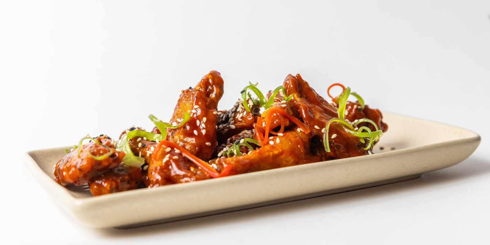 Plate of chicken wings with garnishes on top.
