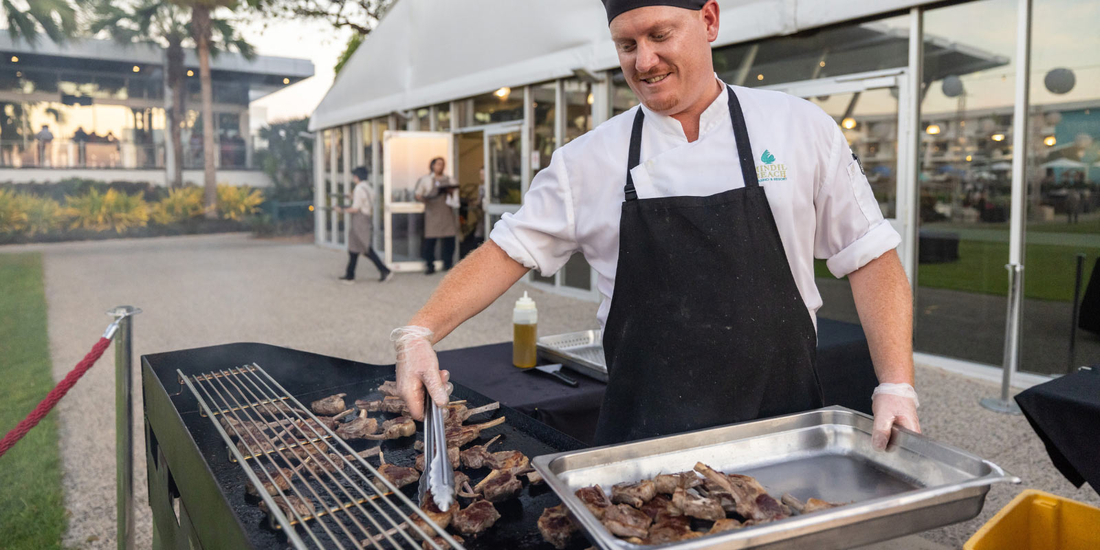 Chef refilling food at an event table.