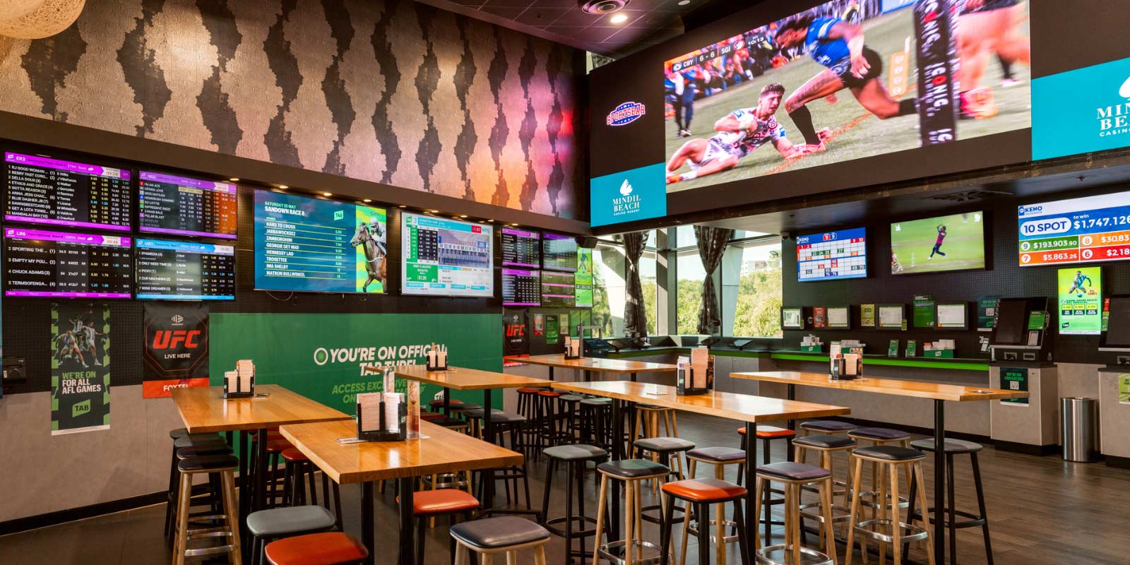 Interior shot of The Sportsbar with TVs, tables and bar stools.